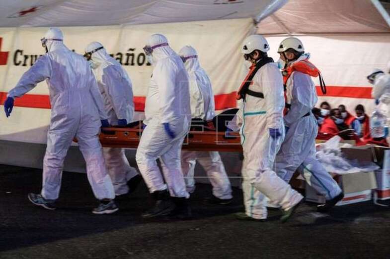 Personal de Salvamento Marítimo y voluntarios de la Cruz Roja transportan un cadáver recuperado de un cayuco / EFE Ángel Medina G.